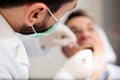Close-up of a young male dentist holding a syringe, giving anesthetic to a mature male patient. High angle view, selective focus o