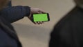 Close up of young male hands holding modern smartphone with green touch screen. Man`s hand shows mobile smartphone with Royalty Free Stock Photo