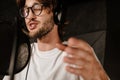 Close up young male singer in headphones emotionally singing in sound recording studio