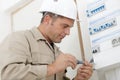 Close-up young male technician examining fusebox with screwdriver Royalty Free Stock Photo