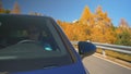 CLOSE UP: Young male tourist drives his blue car along a scenic mountain road