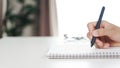 Close up of young man in casual cloth hands writing down on the notepad, notebook using ballpoint pen on the table Royalty Free Stock Photo