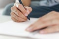 Close up of young man in casual cloth hands writing down on the notepad, notebook using ballpoint pen on the table Royalty Free Stock Photo