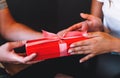 Close up of young man giving his girlfriend red gift box with pink ribbon Royalty Free Stock Photo