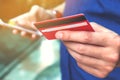 Close up of young man holding credit card and using smart phone