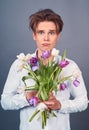 Close-up, a young man holds in a rumpled broken bouquet of tulips