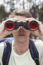 Close-up of young man looking through binoculars in forest