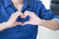 Close-up of a young man making a heart shape with fingers. Space for text. Concept of celebrating Valentine`s Day Royalty Free Stock Photo