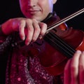 Close up young man playing violin. Selective focus on hand. Studio shot on dark background. Music passion, hobby concept