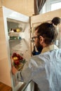 Close up of young man, professional cook in apron taking ingredients out of the fridge while getting ready to prepare a Royalty Free Stock Photo