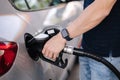 Close-up of young man refuelling a car at a petrol station. Middle selection of human hand hold fuel pump