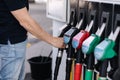 Close-up of young man refuelling a car at a petrol station. Middle selection of human hand hold fuel pump