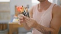 Close-up of a young man\'s hands holding paintbrushes in an art studio, suggesting creativity and artistry