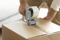 Close up young man sealing big cardboard box. Royalty Free Stock Photo