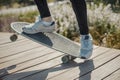 Close up of young man in sneakers riding longboard or skateboard in the park.