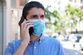 Close up young man with surgical mask calling with mobile phone in city street Royalty Free Stock Photo