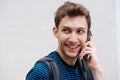 Close up young man talking with cellphone and smiling by white wall Royalty Free Stock Photo