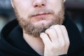 Close-up, a young man touches his beard with his hand. Royalty Free Stock Photo
