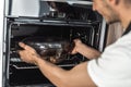 Young man warming up dinner in the oven Royalty Free Stock Photo