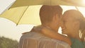 CLOSE UP: Young man and woman gaze into each other`s eyes while twirling in the spring rain under a small yellow umbrella