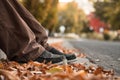 Close Up Of Young Mans Feet In Autumn Leaves on Ground By Curb.