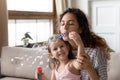 Close up mother blowing soap bubbles with little daughter