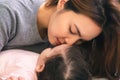 Close up young mother kissing her baby or infant girl while adorable toddler daughter sleeping on bed with love. Beautiful single Royalty Free Stock Photo