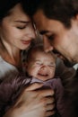 Close up of young parents holding and kissing their newborn baby indoors at home Royalty Free Stock Photo