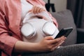 CLose up of young pregnant woman applying headphones on belly headphones enjoying relaxing music, listening to playlist from Royalty Free Stock Photo