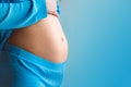 Close-up of young pregnant woman& x27;s belly on blue color background. Motherhood and baby expectation concept Royalty Free Stock Photo