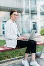 Close-up of young professional businesswoman using her laptop outside while working at modern business center