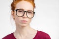 Redhead woman in glasses with hair knot looking at camera on white background Royalty Free Stock Photo