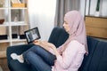 Close-up of young sick Muslim woman talking with her doctor through video chat on tablet pc, showing him blister with