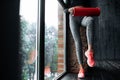 Close-up of a young slender woman in sports leggings kneading the rectus muscle of the thigh with a fascia massager.