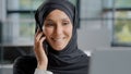 Close-up young smiling arab woman secretary in hijab talking on phone in office female sales agent consult client remote