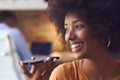 Close Up Of Young Smiling Businesswoman Working At Desk In Office Talking Into Mic Of Mobile Phone Royalty Free Stock Photo