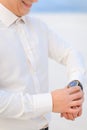 Close up young smiling man standing in winter steppe and looking at watch. Royalty Free Stock Photo