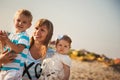 Close up of young smiling mother hugging her small kids, having fun at beach together, happy lifestyle family concept Royalty Free Stock Photo