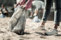 Close up of young student wearing jeans and sneakers cleaning up trash on the beach Royalty Free Stock Photo