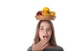 Close up of young surprised woman which is holding a wooden bowl with fruits: apples, oranges, lemon. Vitamins and healthy eating. Royalty Free Stock Photo