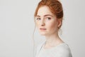 Close up of young tender beautiful ginger girl with blue eyes looking at camera over white background. Copy space.