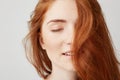 Close up of young tender beautiful girl with red hair smiling with closed eyes over white background.