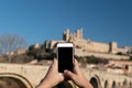 Close-up of a young tourist taking a photo with her smartphone of a medieval castle