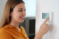 Close up of young woman adjusting central heating temperature at home on thermostat. Turn down the temperature for energy saving Royalty Free Stock Photo