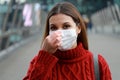 Close up of young woman adjusting protective mask on nose looks at camera outdoors