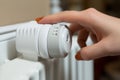 Close-up of young woman adjusting thermostat temperature on radiator. Energy saving mode concept. Generative Ai