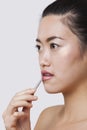 Close-up of young woman applying lip gloss with brush over white background Royalty Free Stock Photo