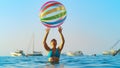 CLOSE UP: Young woman in bikini plays with huge inflatable ball on sunny evening Royalty Free Stock Photo