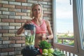 Close up of young woman with blender and green vegetables making detox shake or smoothie at home Royalty Free Stock Photo