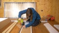 CLOSE UP: Young woman in blue hoodie assembles furniture with a power drill.